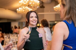 Woman enjoying a glass of champagne while engaging in conversation at a corporate networking event, captured by Light Planning Media’s event photography services
